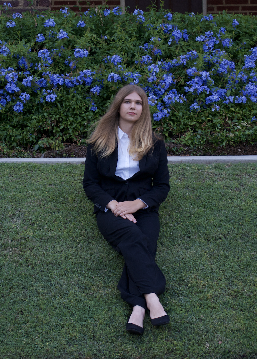 A photo of me sitting on grass with blue flowers in the background